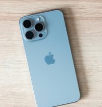 Close-up of a modern smartphone on a light wooden table surface.