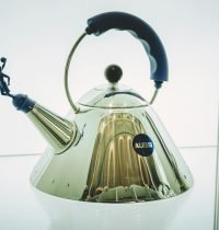 Close-up of a sleek Alessi kettle featuring a unique blue handle design.